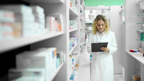 Pharmacist walking by shelf with medicines checking inventory - pharmacy
