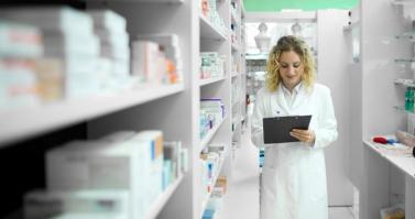 Pharmacist walking by shelf with medicines checking inventory - pharmacy